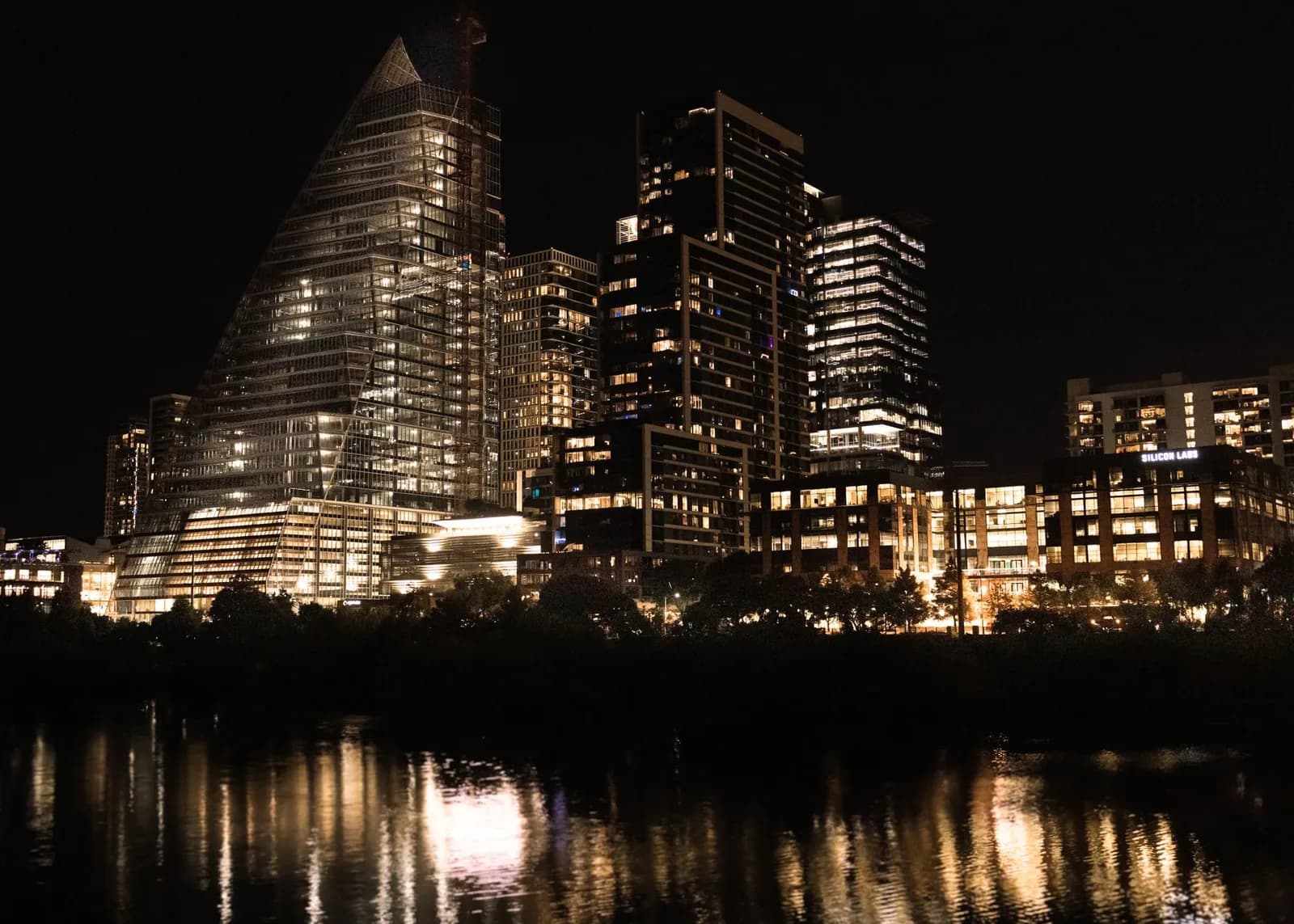 Illuminated skyscrapers reflecting in the river at night in downtown Austin, Texas.
