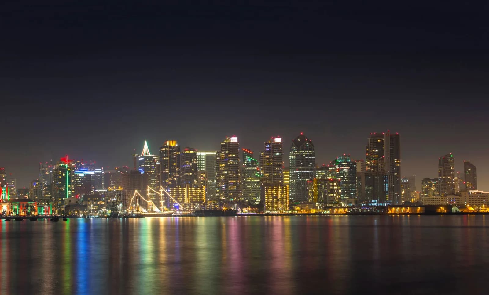 A serene night view of San Diego's illuminated skyline reflecting on calm water.