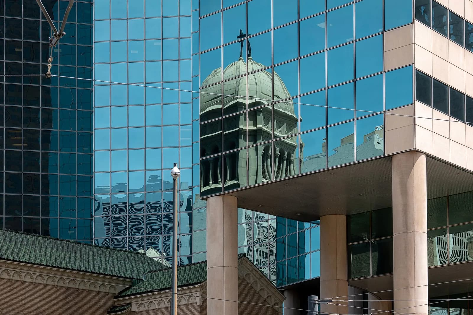 Historic dome reflected in a glass skyscraper, creating a juxtaposition of old and new architecture.