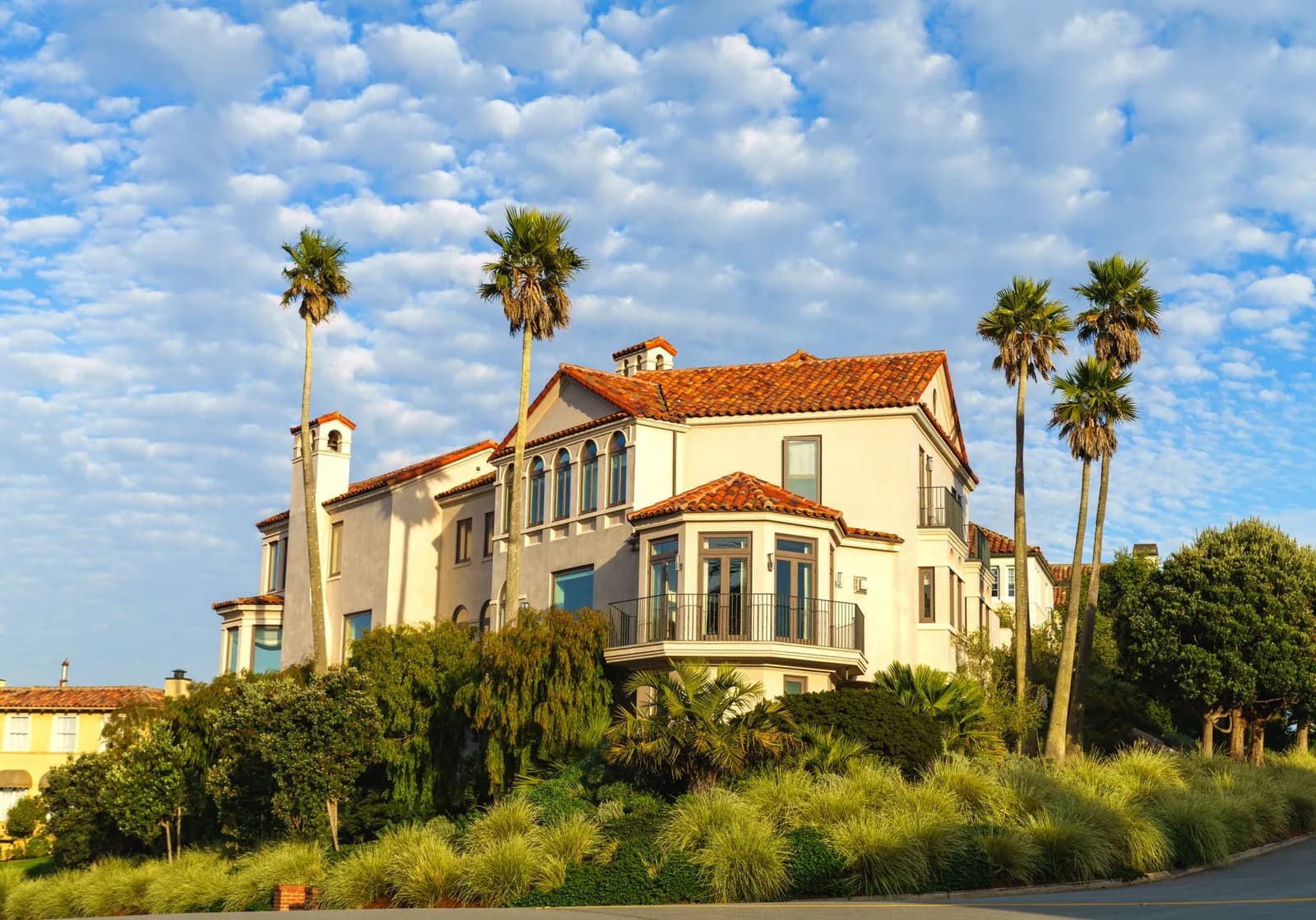 Elegant Mediterranean villa surrounded by palm trees under a bright blue sky.
